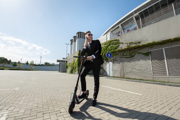 Zakenman die zich naast een elektrische autoped bevindt