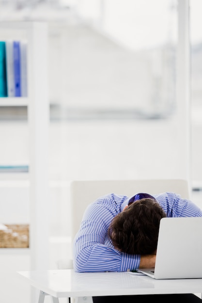 Zakenman die zijn hoofd op bureau neerzet