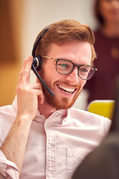 Zakenman dragen headset praten met beller in drukke klantenservicecentrum