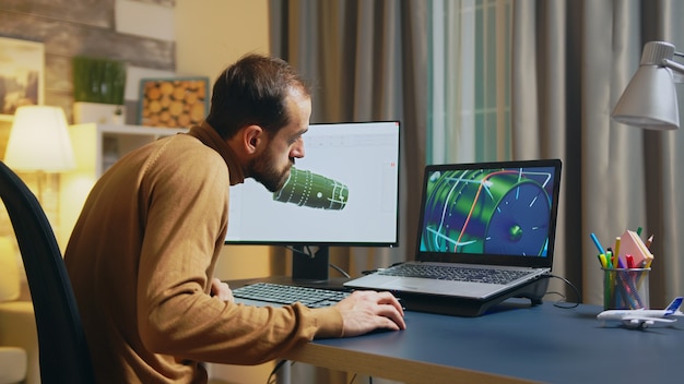 Zakenman en ingenieur die moderne software gebruiken om 's nachts een turbine op de computer in het thuiskantoor te ontwerpen.