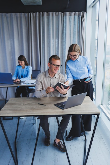 Zakenman en vrouwelijke collega werken in modern kantoor op laptop Collega's op kantoor praten op het werk en werken aan een nieuw project Mensen uit het bedrijfsleven op kantoor