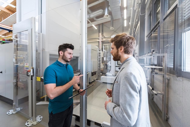 Zakenman en werknemer bespreken in moderne fabriek