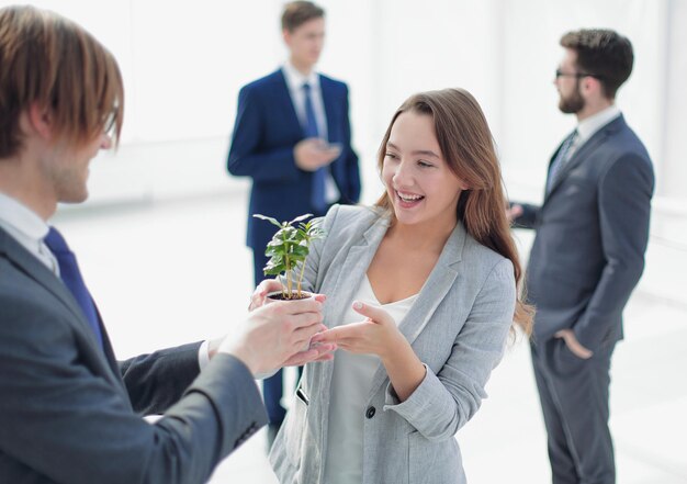 Zakenman en zakenvrouw met een pot met spruiten