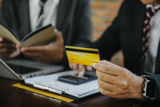 Zakenman gebruikt 's ochtends een creditcard met een rekenmachine voor internetbetalingen op kantoor