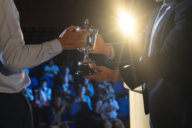 Foto zakenman geeft trofee aan zakelijke mannelijke leidinggevende op het podium in het auditorium