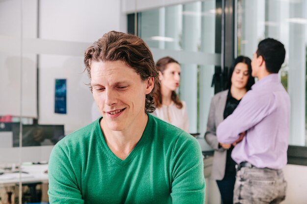 Zakenman glimlacht terwijl collega's op de achtergrond staan op de werkplek