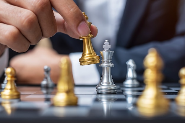 Zakenman hand gouden schaak koning figuur verplaatsen tijdens schaakbord concurrentie.