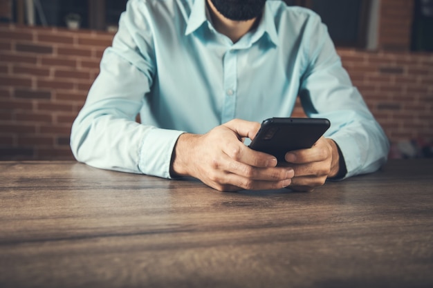 Zakenman hand met slimme telefoon op tafel