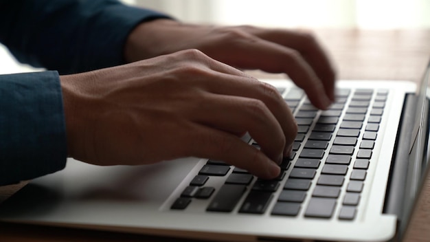 Zakenman hand werkt op capabele laptopcomputer aan kantoor tafel close-up shot