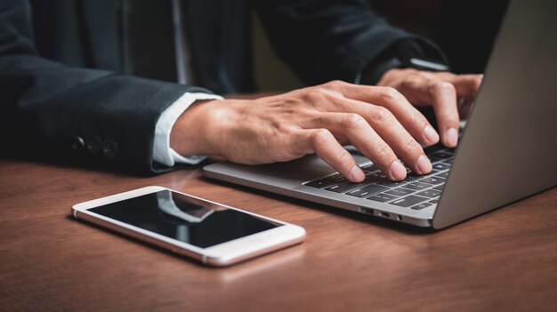 Zakenman handen met laptop tijdens het werken op kantoor, zakenman met behulp van laptop op kantoor, notebook op houten tafel, bedrijfsconcept