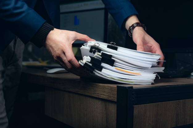 Zakenman handen werken in stapels documenten van papieren dossiers