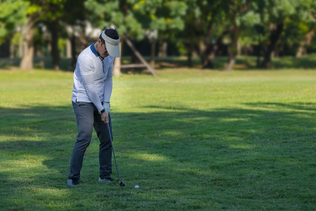 Zakenman het praktizeren golf op het lange gras op de golfcursus in het park