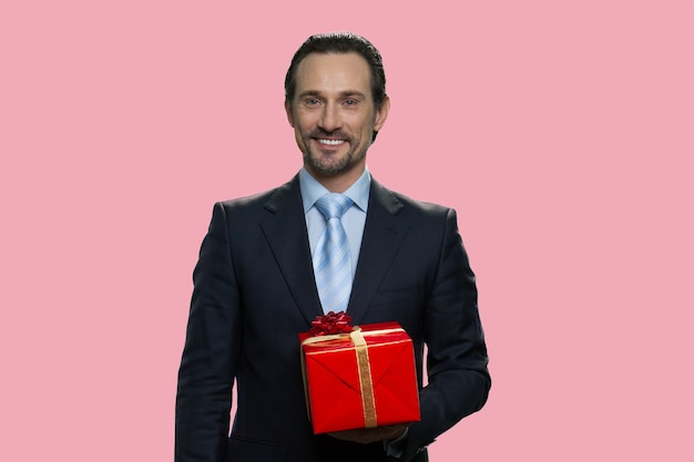 Zakenman houdt een geschenkdoos. Geïsoleerd op roze achtergrond.