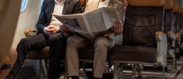 Zakenman in bruin pak op reis met zakelijke krant tijdens het lezen in het vliegtuig tijdens de vlucht