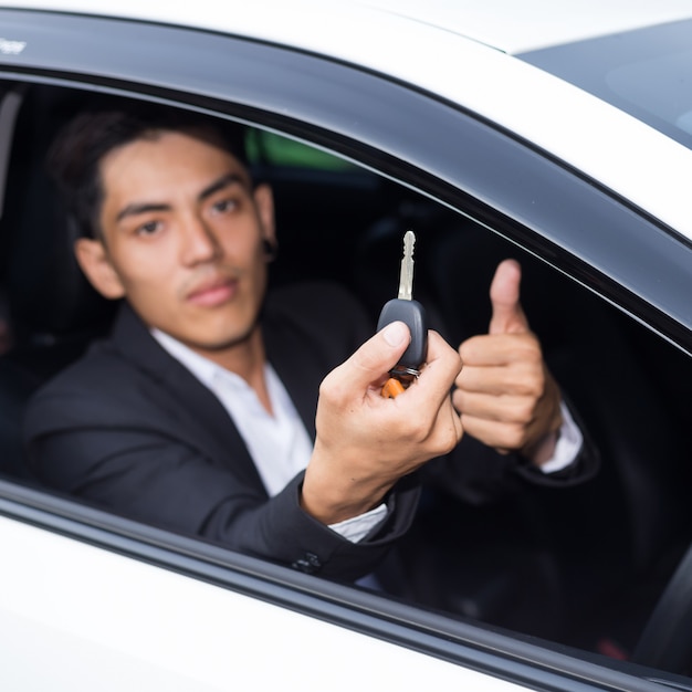 Zakenman in een pak en met een autosleutel in zijn hand