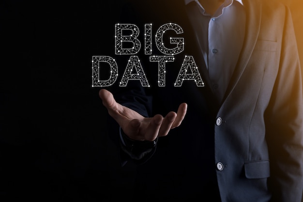 Zakenman in een pak op een donkere muur heeft het opschrift big data. opslag netwerk online server concept.social netwerk of business analytics vertegenwoordiging.