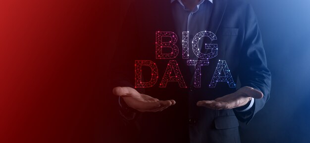 Zakenman in een pak op een donkere muur heeft het opschrift big data. opslag netwerk online server concept.social netwerk of business analytics vertegenwoordiging.