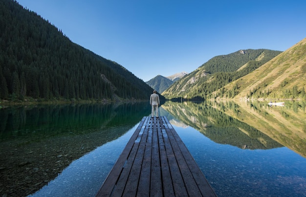 zakenman in een wit pak staat op een pier bij het meer