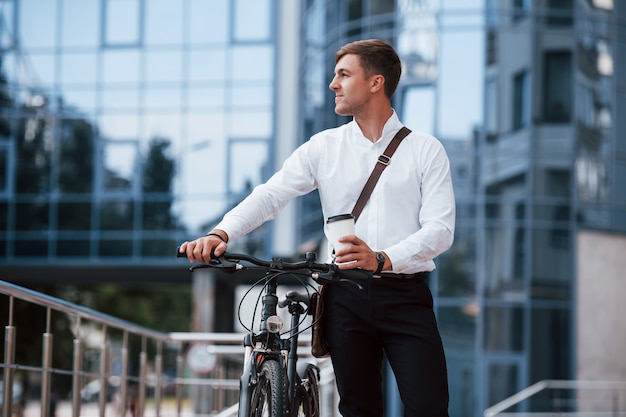 Zakenman in formele kleding met zwarte fiets is in de stad.