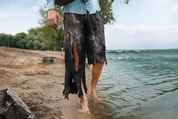 Zakenman in gescheurd pak wandelen op het strand op verloren eiland. Bedrijfsrisico, ineenstorting of faillissementsconcept