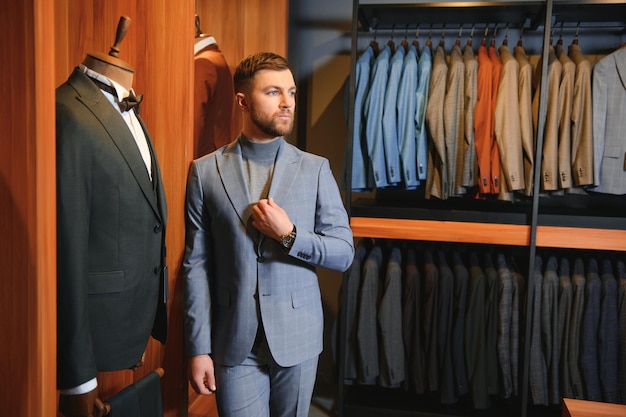 Zakenman in klassiek vest tegen rij pakken in de winkel