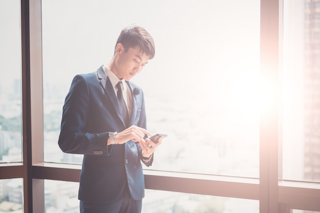 Zakenman in kostuum en het gebruiken van moderne smartphone in zijn bureau. Concept voor zaken