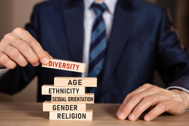 Foto zakenman in pak gebouw toren van houten blokken met tekst diversiteit, etniciteit, gelijkheid, leeftijd, seksuele geaardheid.
