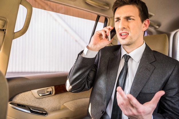 Zakenman in zijn luxe auto en praten over de telefoon.