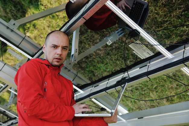 zakenman ingenieur met behulp van laptop bij zonnepanelen plant eco-energieveld op de achtergrond