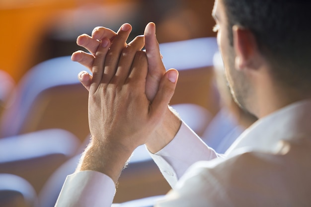 Zakenman klappen tijdens het luisteren naar spraak in het conferentiecentrum