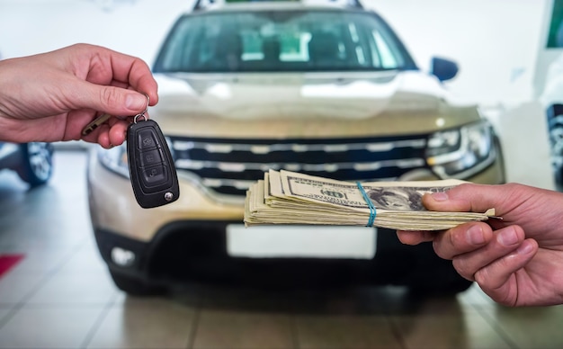 Zakenman koopt nieuwe auto in showroom die dollarsgeld geeft en sleutels neemt van auto, financiënconcept