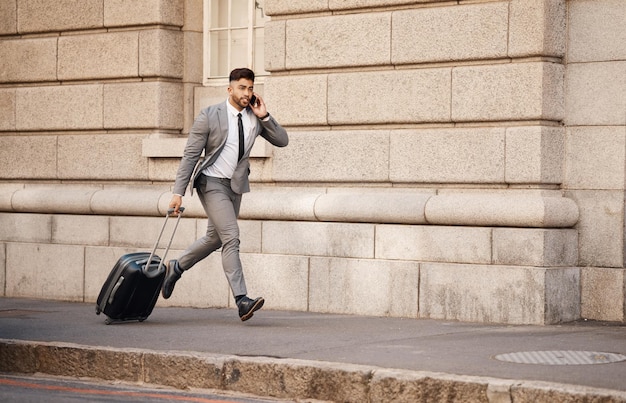 Zakenman laat en en rennen op telefoongesprek in de stad met woon-werkverkeer en reizen naar het werk Stedelijke weg en professionele persoon met mobiel netwerken en stress in een straat met ondernemer en bagage