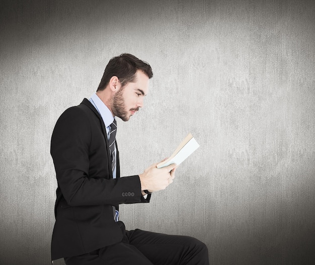 Zakenman liggend op de vloer tijdens het lezen van een boek tegen een witte en grijze achtergrond