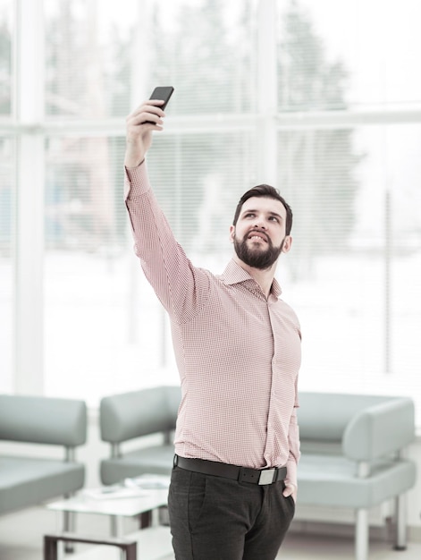 Zakenman maakt selfie terwijl hij bij het raam op kantoor staat