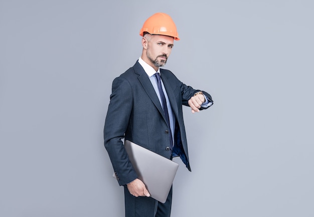 Zakenman man in het bouwen van helm houden laptop tijd controleren, op schema.