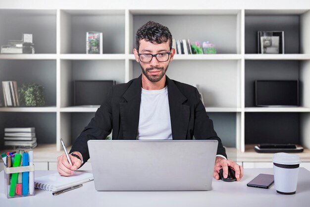 Foto zakenman met behulp van laptop op kantoor geconcentreerde werknemer het maken van aantekeningen in het kantoor