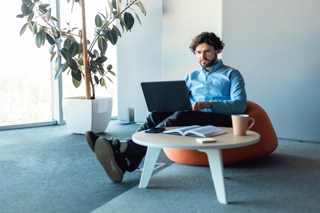 Zakenman met behulp van laptop zit aan bureau in kantoor