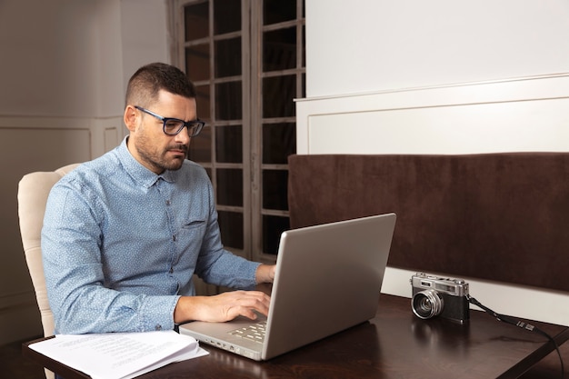 Zakenman met bril en shirt werkt op zijn laptop vanuit huis