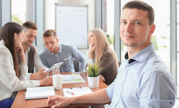 Zakenman met collega's op de achtergrond in kantoor