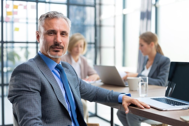 Foto zakenman met collega's op de achtergrond in kantoor