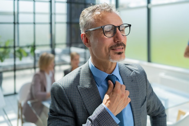 Zakenman met collega's op de achtergrond in kantoor