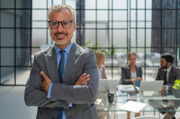 Zakenman met collega's op de achtergrond in kantoor