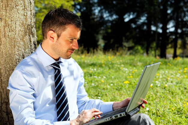 Zakenman met computer in een park in de zomer