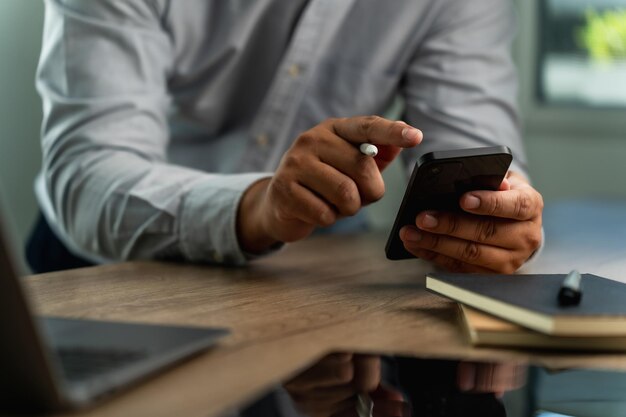 Foto zakenman met een smartphone in het kantoor die online werkt op zoek naar mobiele communicatie- en technologieconcepten