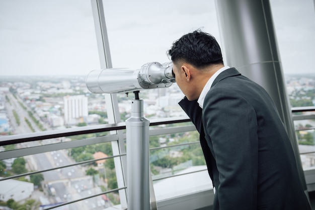 Zakenman met een verrekijker op de top van het gebouw op zoek naar gouden kans concept