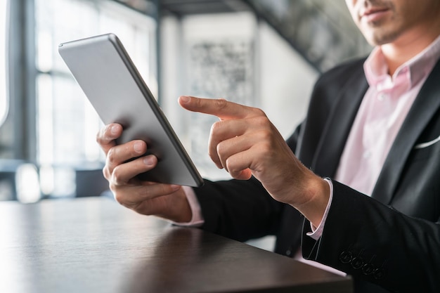 Zakenman met grijze digitale tablet in de hand scrollen Close-up van mannelijke handen met apparaat in kantoorruimte zakenman in zwart pak gebruik van draagbaar apparaat binnenshuis concept van werk