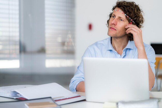 Zakenman met hoofdband die aan zijn bureau droomt