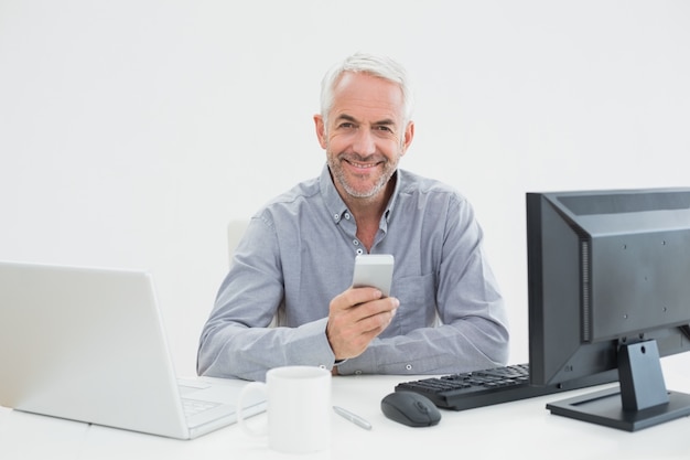 Zakenman met mobiel, laptop en computer op het bureau