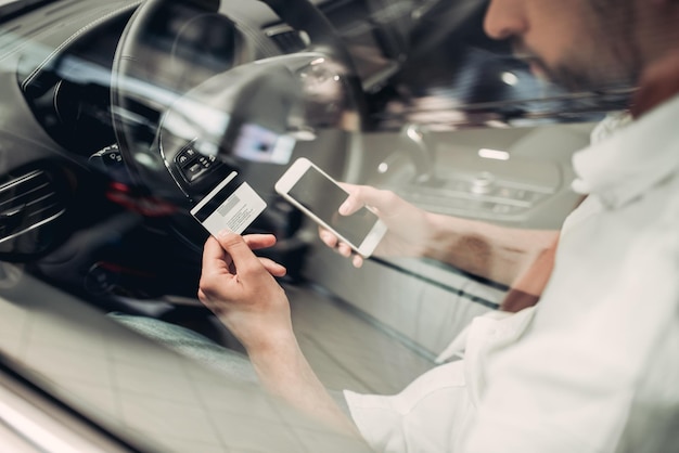 Zakenman met smartphone en creditcard die online in de auto winkelt