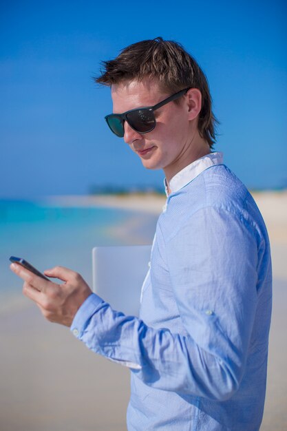 Zakenman met telefoon in hand op een tropisch strand